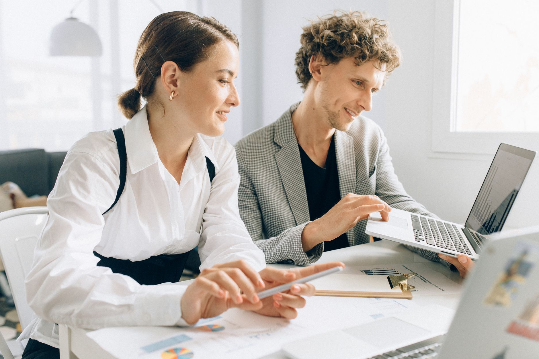 engagement website - Two colleagues collaborating on a project, using laptops and documents in a modern office setting.