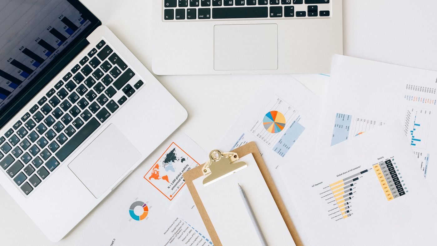 Illustration: Nataliya Vaitkevich / Pexels Overhead view of two laptops surrounded by printed charts and a clipboard