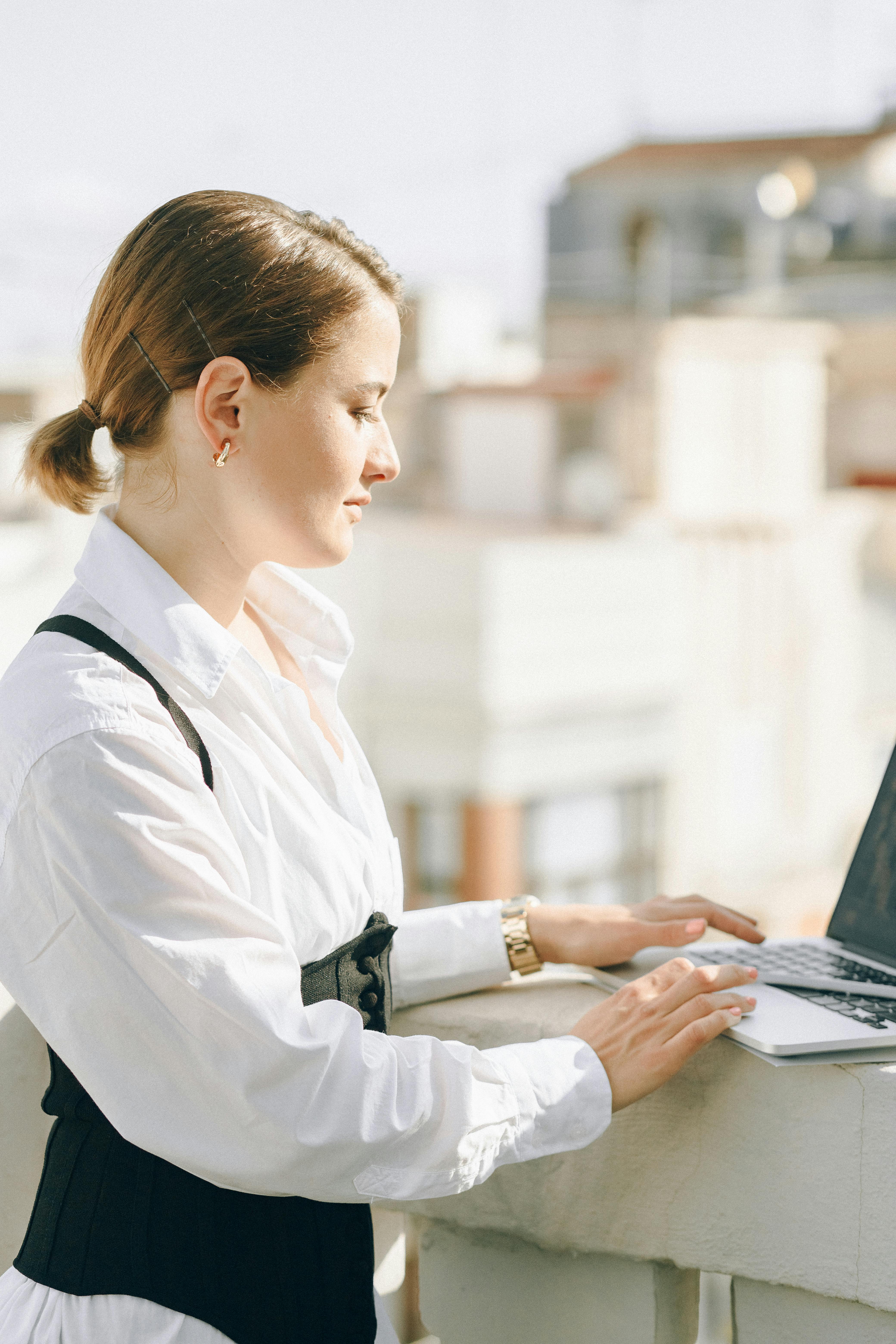 woman in white dress shirt using laptop computer