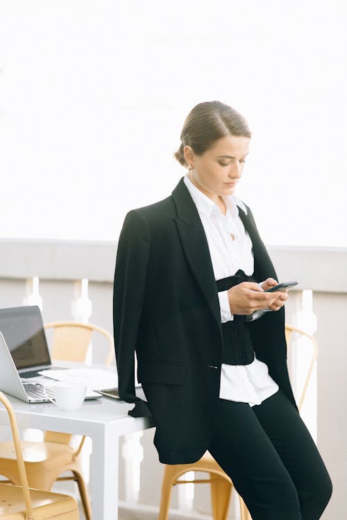 Free Woman in Black Blazer Using a Cellphone while Standing Stock Photo