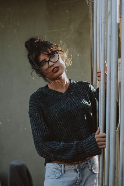 Portrait of a young woman in glasses and a sweater, captured outdoors in natural light.