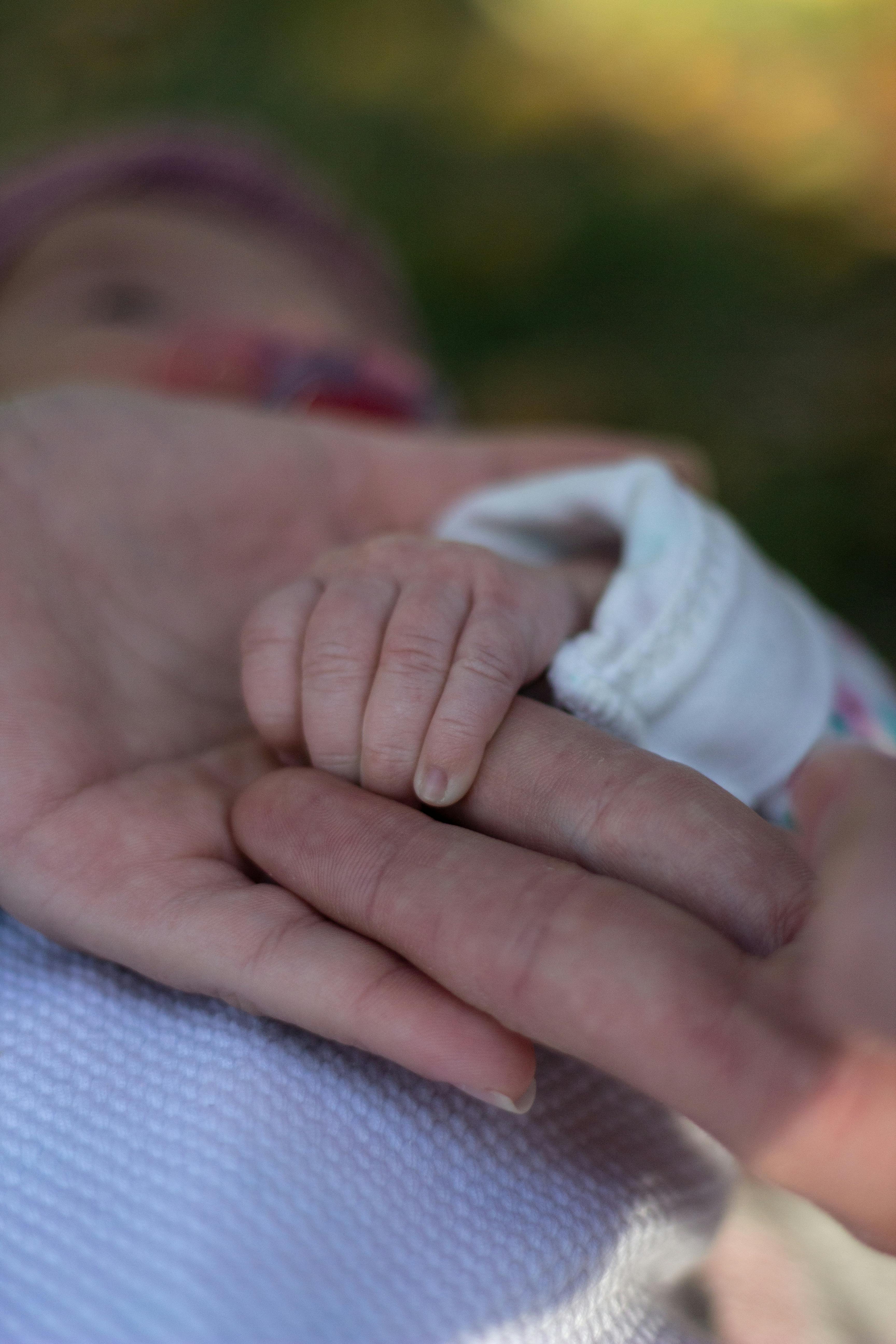 a newborn baby holding the person s finger