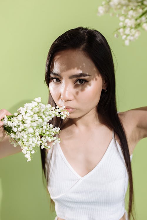 Stylish Woman in White Tank Top holding White Flowers 