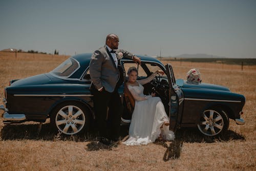 Newlyweds Posing with Car on Field