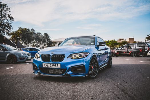 A Blue Car Parked on an Asphalt Road Near Different Cars