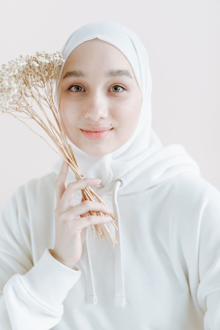 A Girl Wearing White Hoodie Holding Dry Flowers