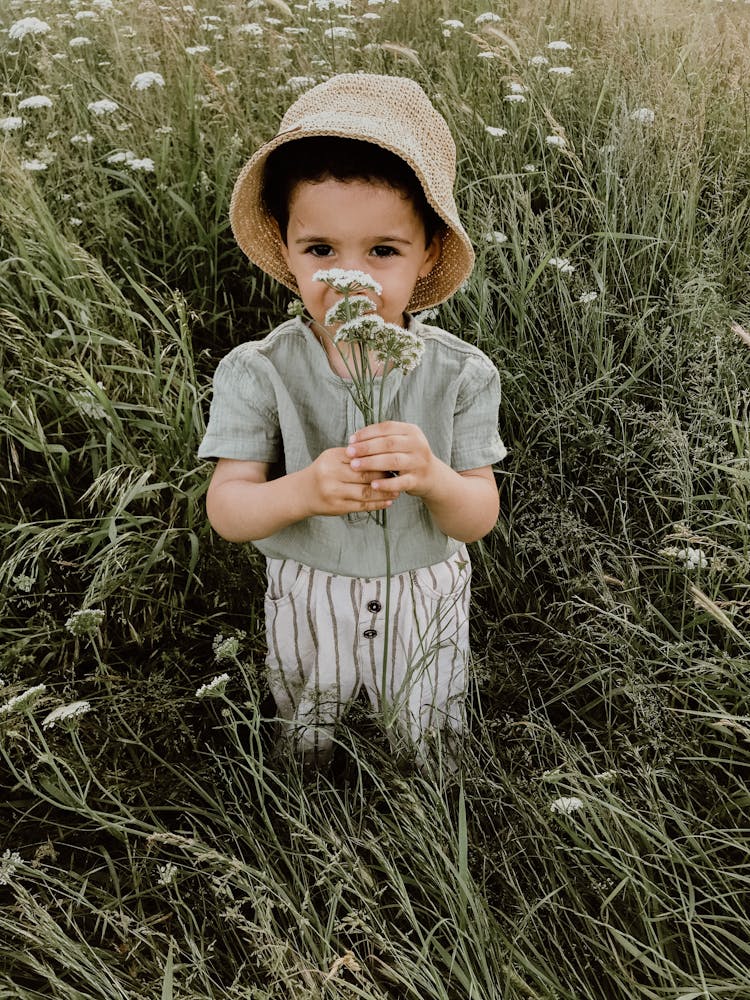 Cute Boy In Hat Smelling Flowers