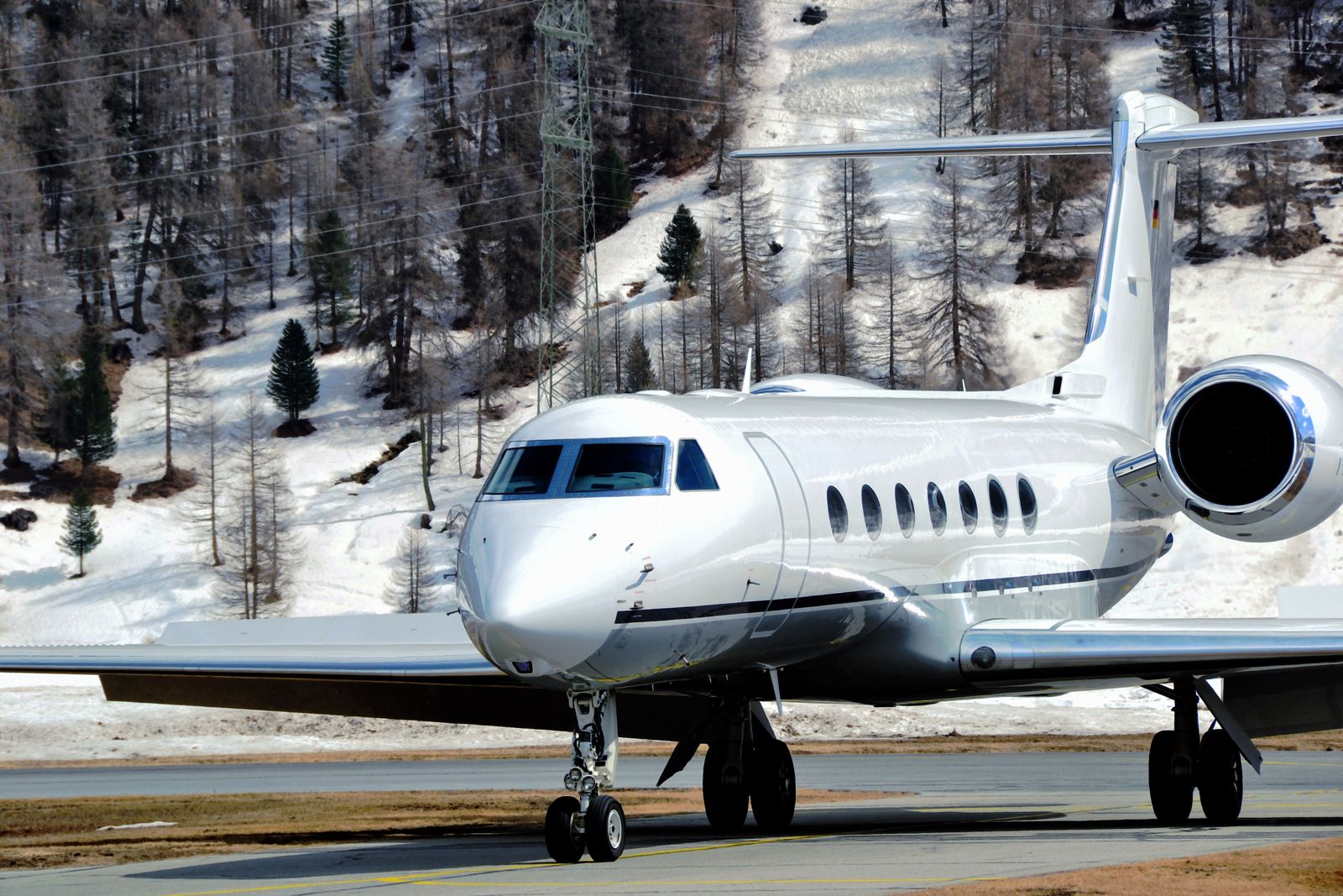 A private jet taxiing on a snowy runway with mountainous backdrop in Samaden, Switzerland