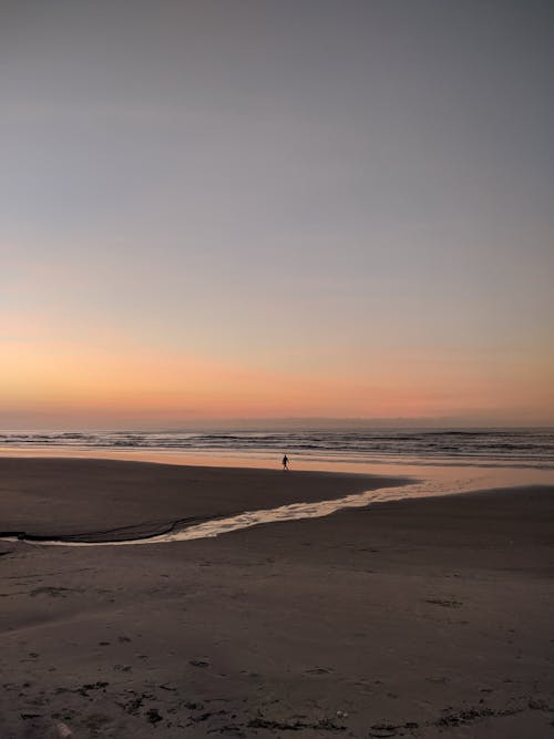 Person Walking on Beach at Dusk