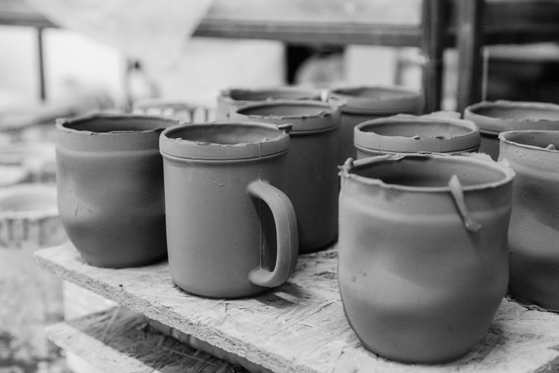 Close crop of unglazed clay mugs drying in rows — photo by ROMAN ODINTSOV on Pexels