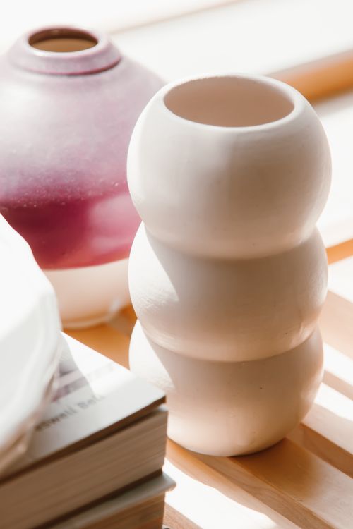 Free Artistic composition of modern ceramic vases and books in natural light, emphasizing elegance and simplicity. Stock Photo