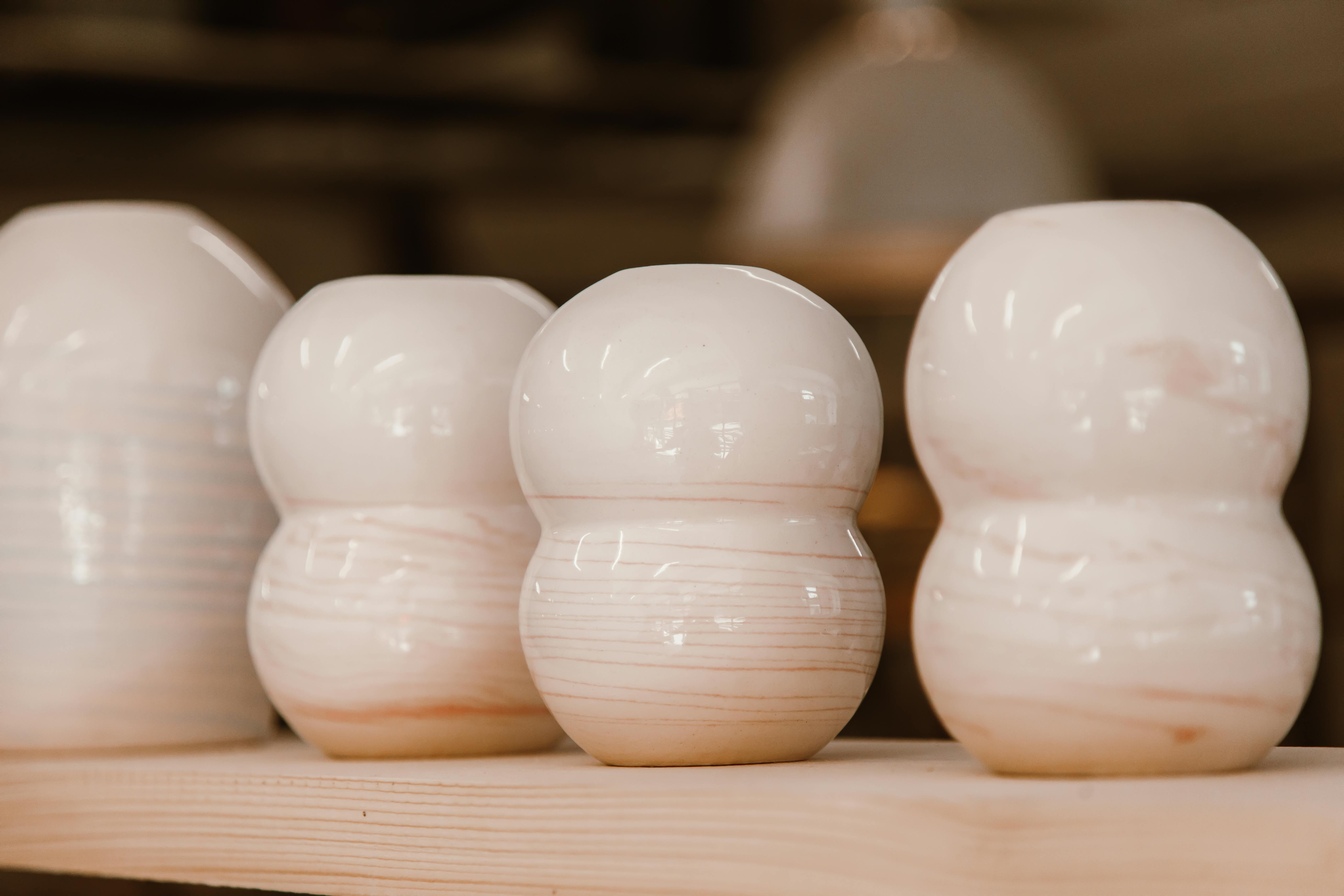 A close-up of modern ceramic vases on a wooden shelf, perfect for interior decor.