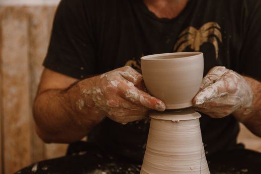 Hands expertly shaping a clay pot on a pottery wheel, showcasing the art of pottery.