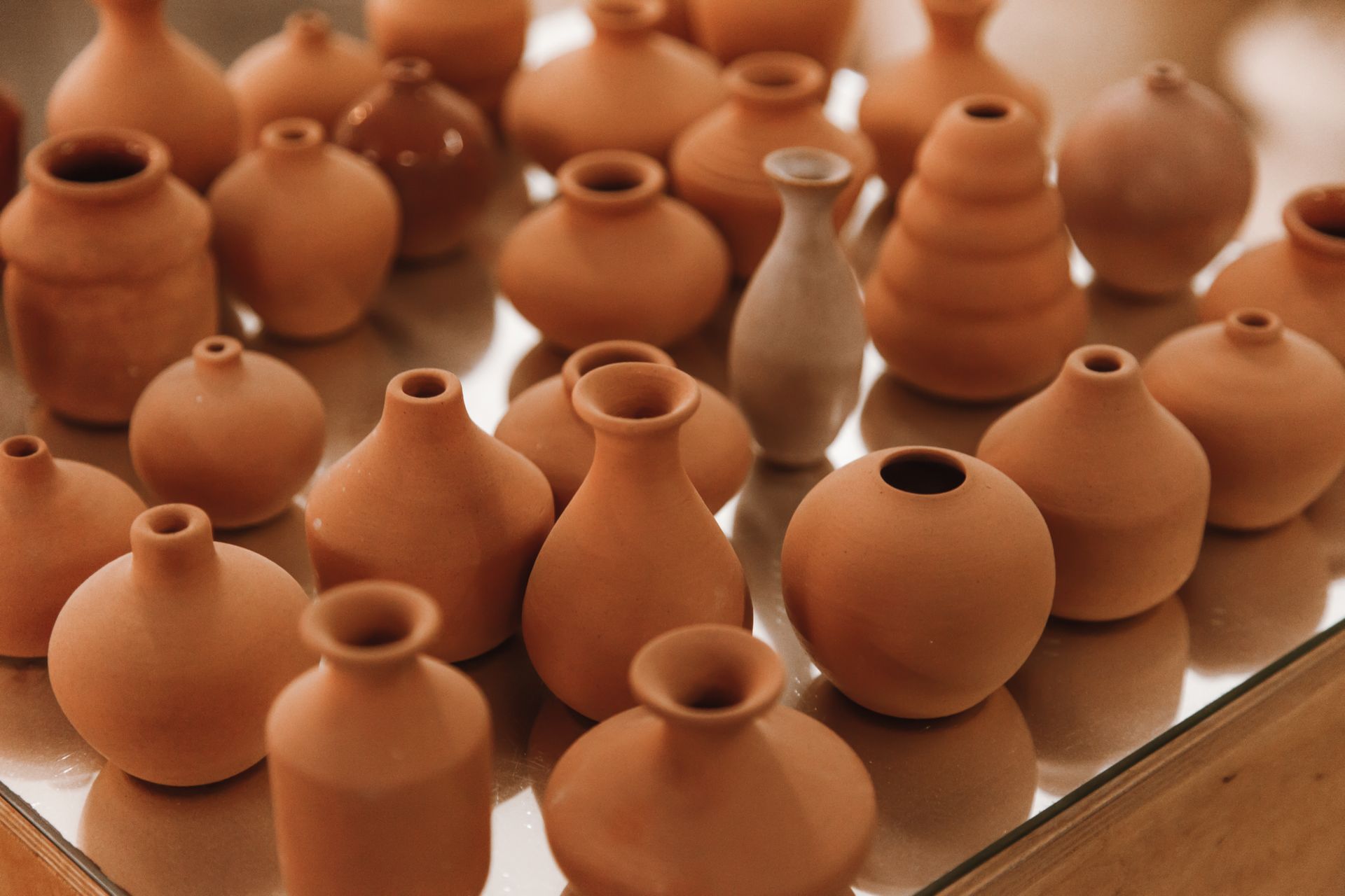 A variety of ceramic pottery displayed on a glossy surface, showcasing craftsmanship.