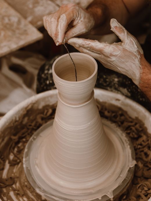 Clay bowls stacked beside a wheel, ROMAN ODINTSOV on Pexels