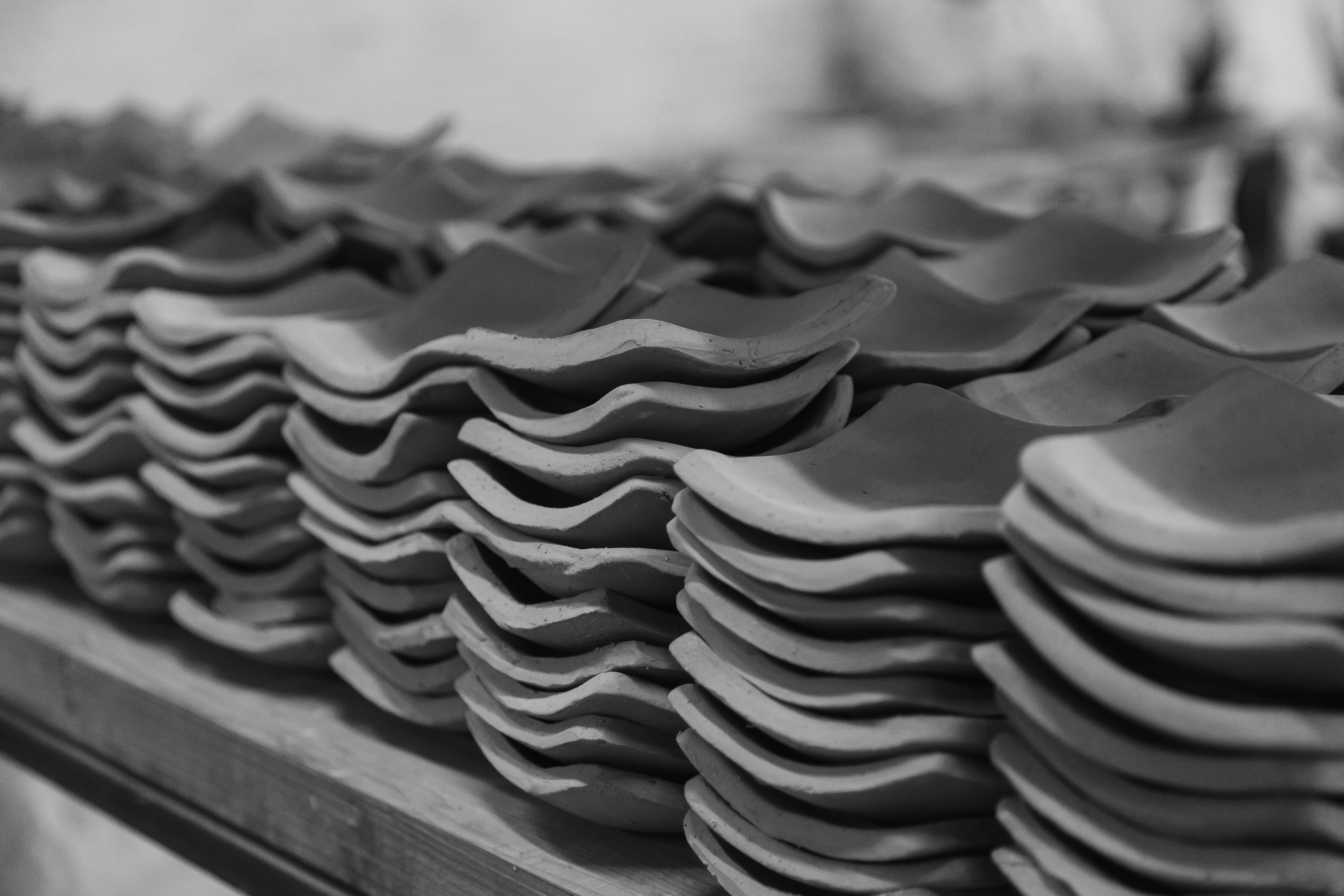 Monochrome image of neatly stacked clay roof tiles in a construction setting.