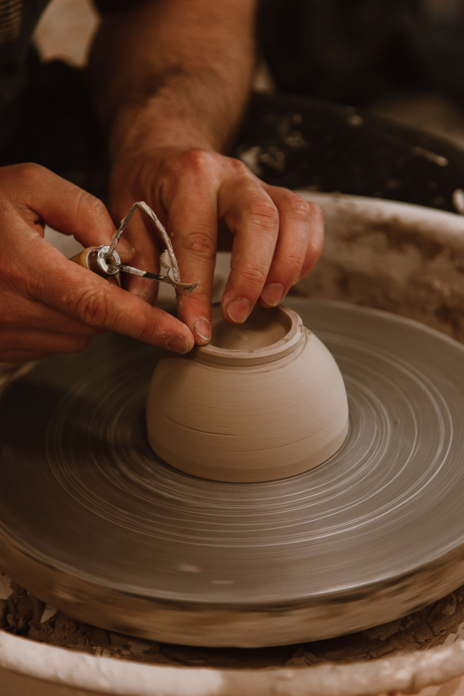 Hands shaping a ceramic bowl on a pottery wheel