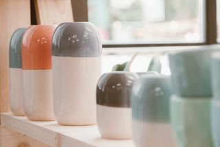 Ceramic vases lined up on a wooden shelf — photo by ROMAN ODINTSOV on Pexels
