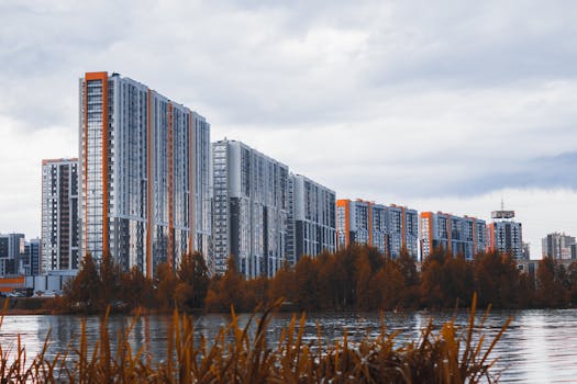 High-rise apartment buildings near a river with autumn foliage.
