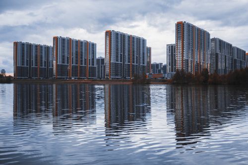 Free Stunning cityscape with modern skyscrapers reflecting on calm waters under a cloudy sky. Stock Photo