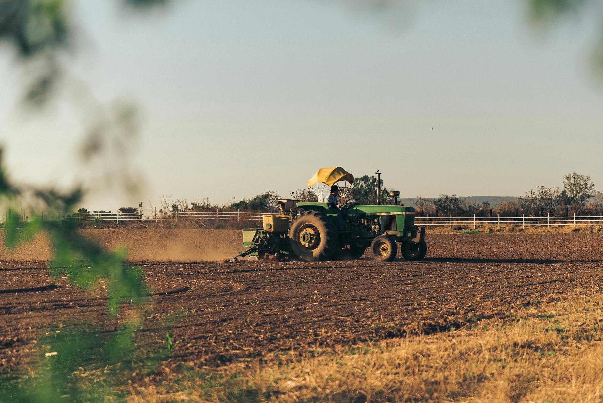 A tractor plows through cropland at dusk, showcasing agricultural life in a rural setting.