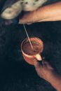 Person Holding a Brown Ceramic Mug while Milking a Cow
