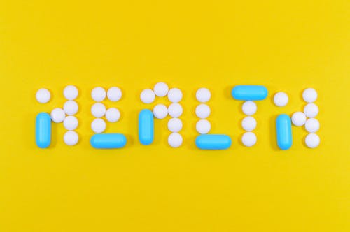 黄色表面上的白色和蓝色健康药和片剂字母抠图