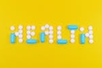 White and Blue Health Pill and Tablet Letter Cutout on Yellow Surface