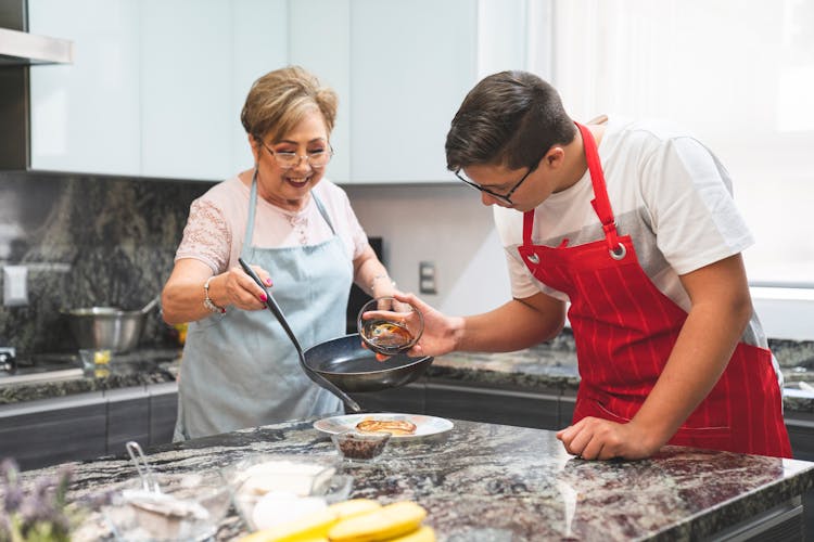 Woman And Man Wearing Aprons Preparing Food In A Kitchen