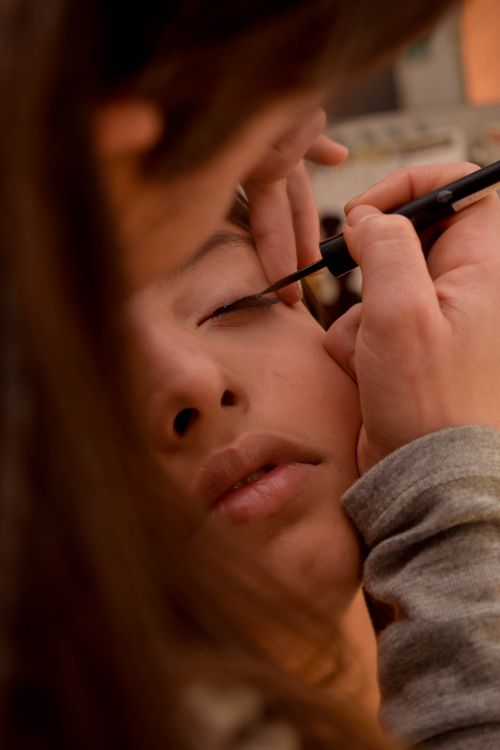 Free Close-up of makeup artist applying eyeliner to a client's closed eyes, focusing on precision and technique. Stock Photo