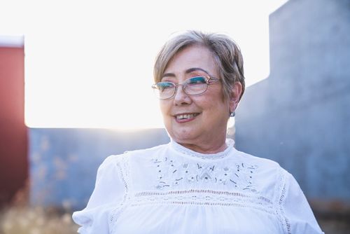 Free Portrait of a smiling senior woman with eyeglasses enjoying a bright outdoor setting. Stock Photo