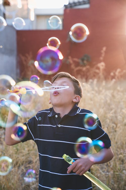 Boy in Black Polo Shirt Playing Blowing Bubbles