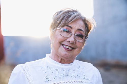 Free Portrait of a smiling senior woman with eyeglasses enjoying a sunny day outdoors. Stock Photo