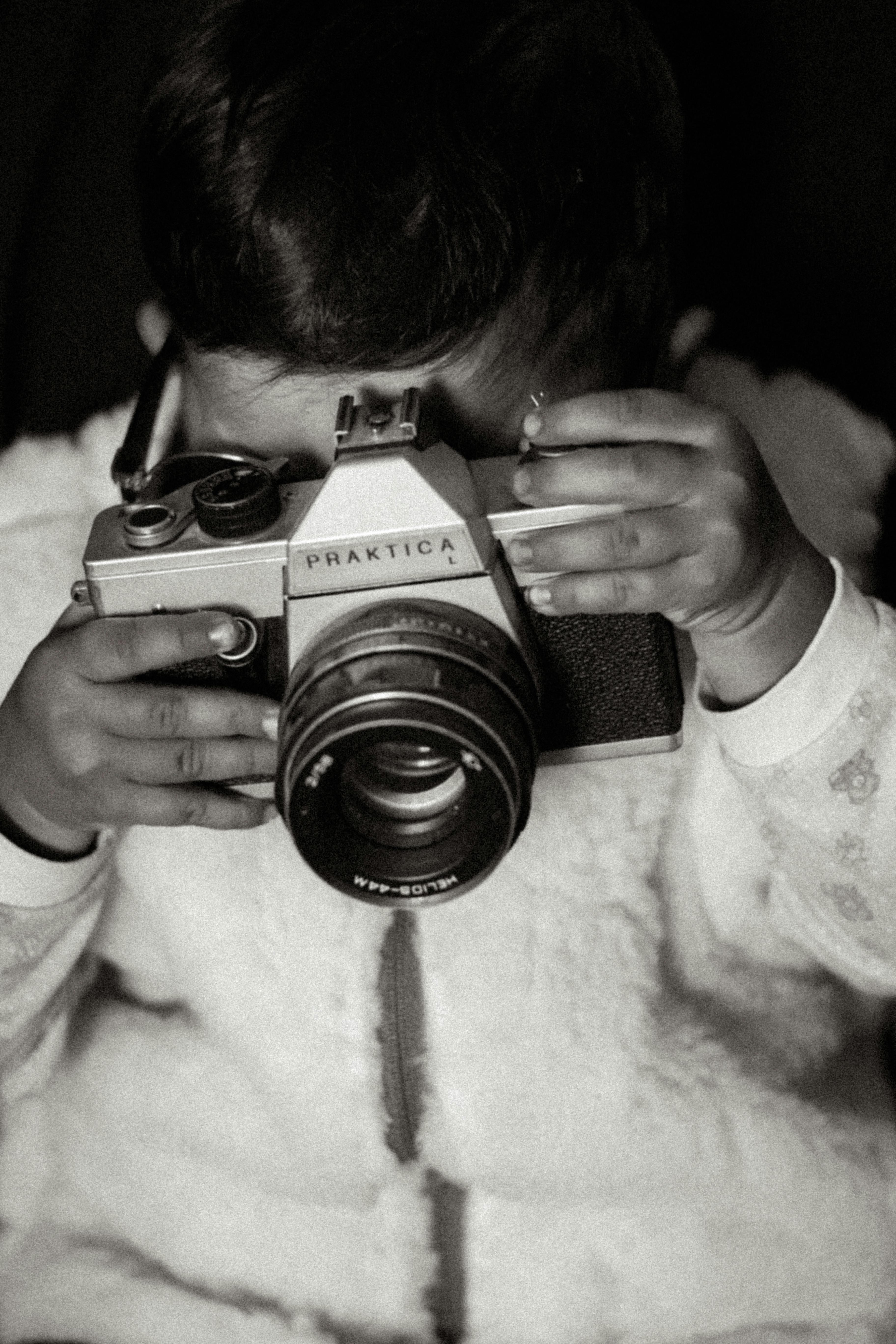 Black and white image of a young child holding a vintage camera, creating a nostalgic vibe.