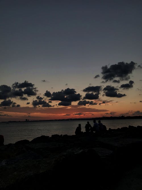 People Sitting on a Coast at Sunset 