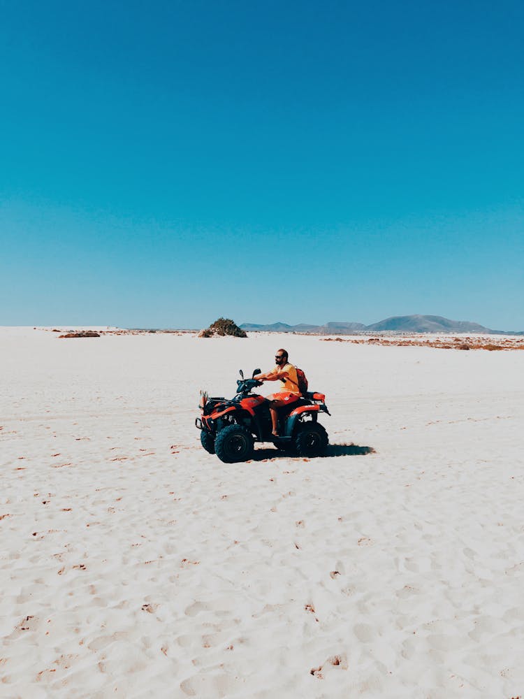 Man Riding An ATV On Sand Dunes