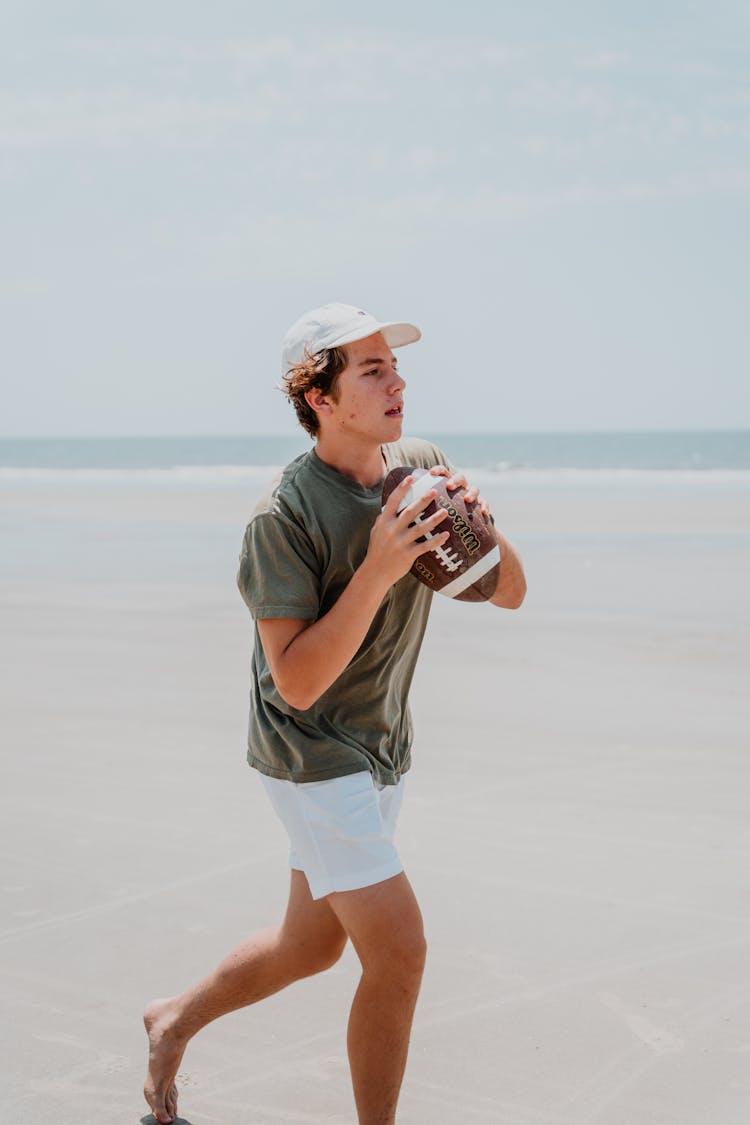 Teenage Boy Holding A Ball At The Beach