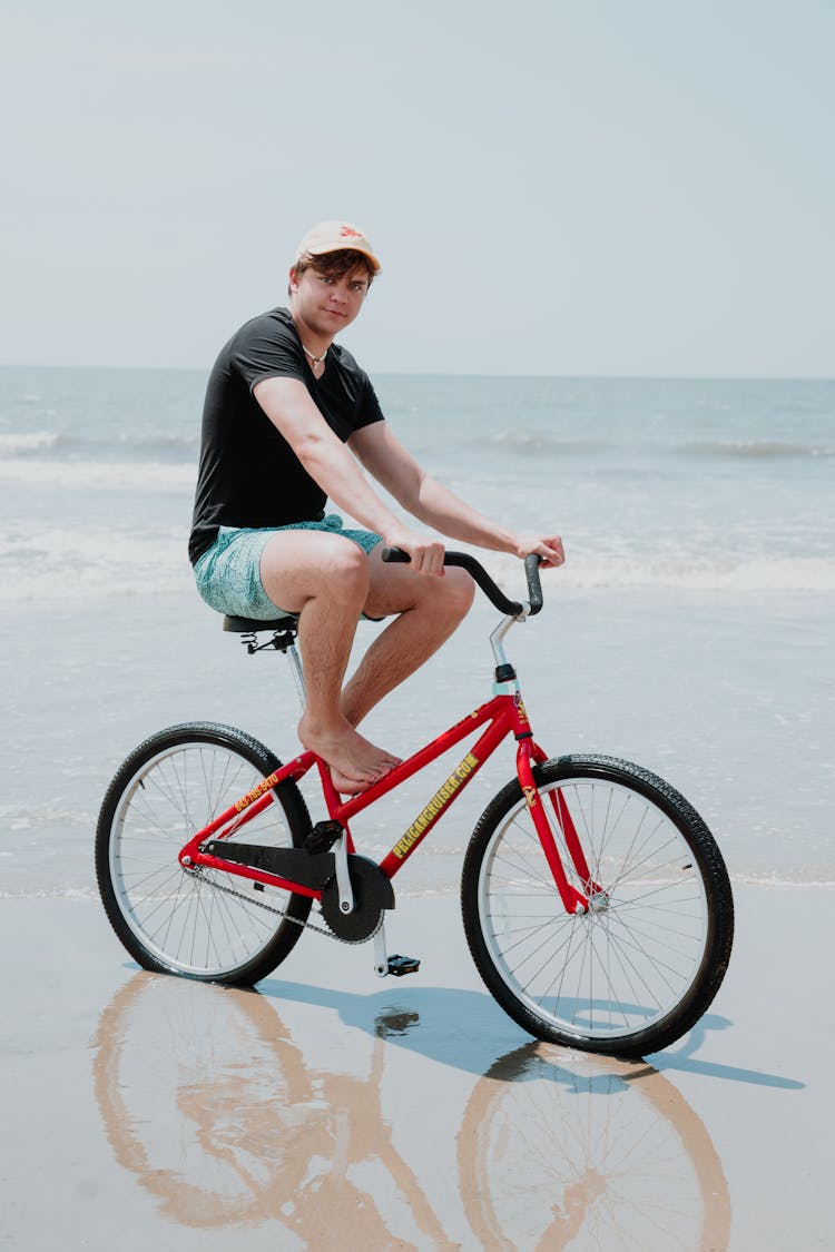 A Man Riding A Bike At The Beach 