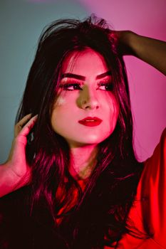 Vibrant studio portrait of a woman with dramatic lighting and red accents, showcasing beauty and elegance.