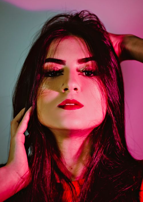 Free Close-up portrait of a woman with creative makeup and red lipstick in vibrant lighting. Stock Photo
