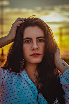 A captivating portrait of a woman with long wavy hair at sunset, creating a dramatic and moody atmosphere.