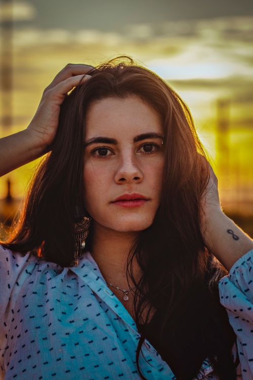 Free A captivating portrait of a woman with long wavy hair at sunset, creating a dramatic and moody atmosphere. Stock Photo