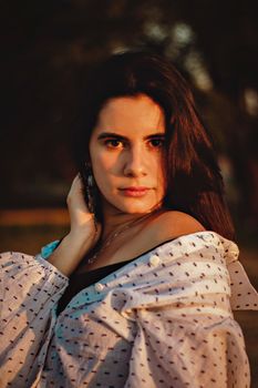 A captivating portrait of a woman outdoors during a warm sunset, exuding confidence and charm.