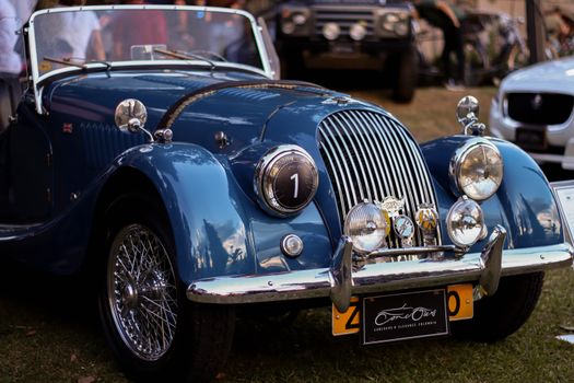 A classic blue vintage car displayed at an outdoor auto exhibition, showcasing its elegant design.