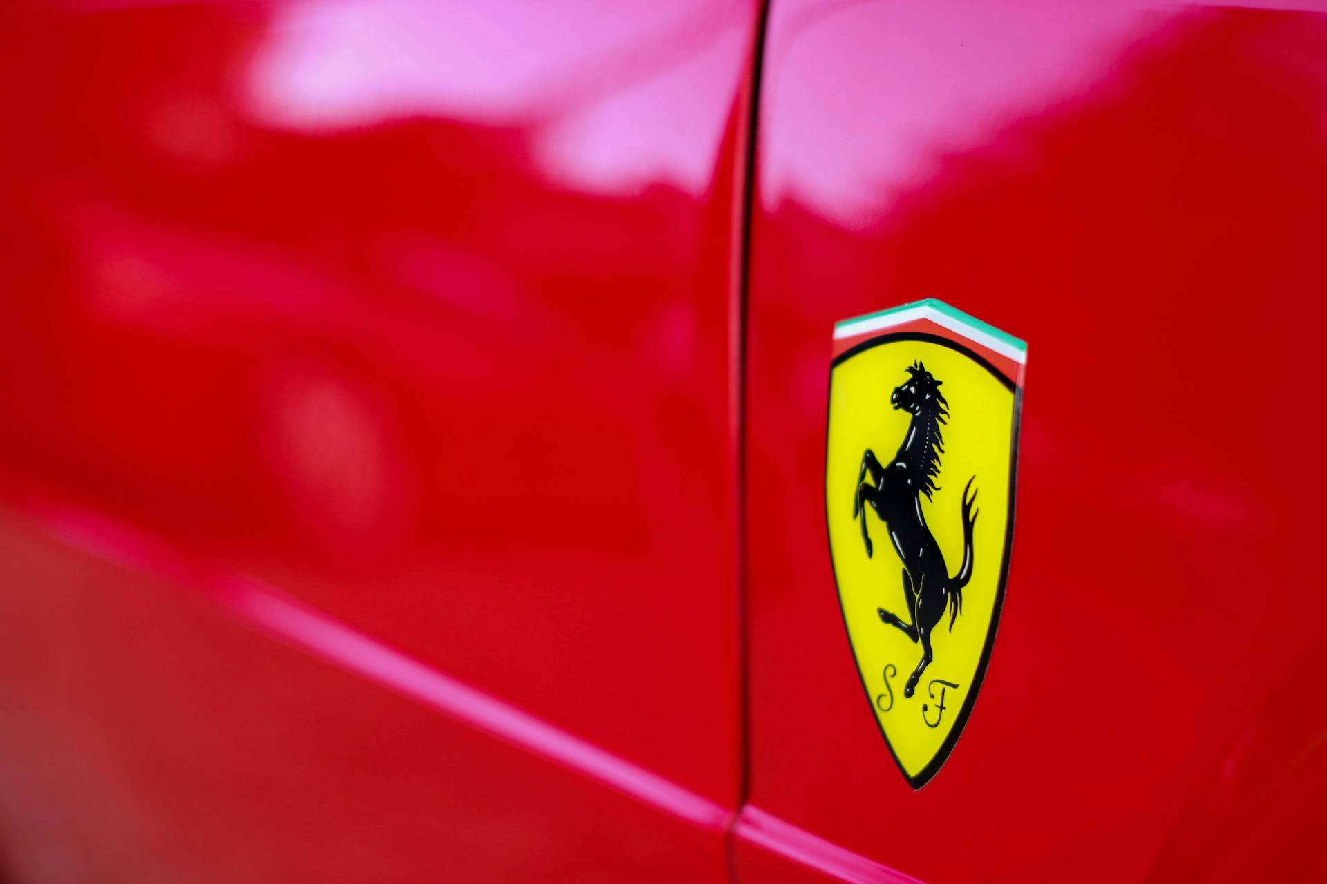 Detailed close-up of a red sports car with a Ferrari emblem, showcasing luxury and design.