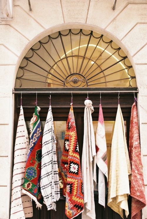 Free Assorted vibrant rugs hanging below an ornate arched window, showcasing traditional patterns. Stock Photo
