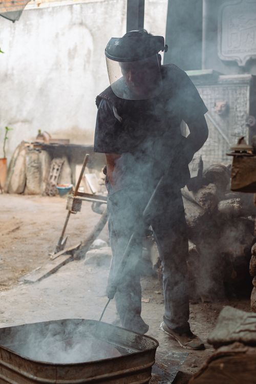 Free Craftsman in face shield creating pottery in a smoky workshop. Stock Photo