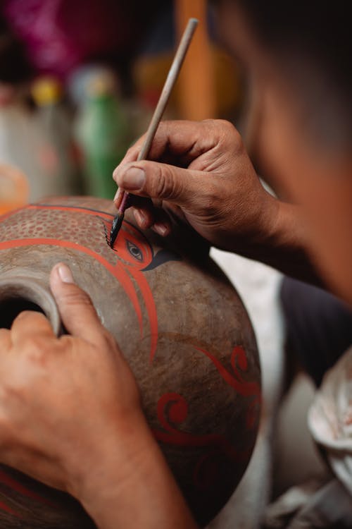 Person Doing Painting on a Round Ceramic Vase