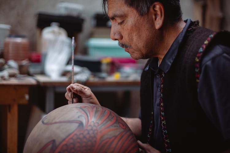 A Man Painting A Ceramic Jar