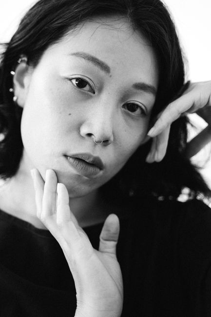 Striking black and white portrait of a woman with a nose piercing, showcasing emotion.